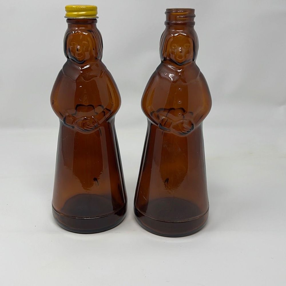 Lot of 2: Amber Glass Mrs. Butterworth Syrup Bottles. One missing lid.